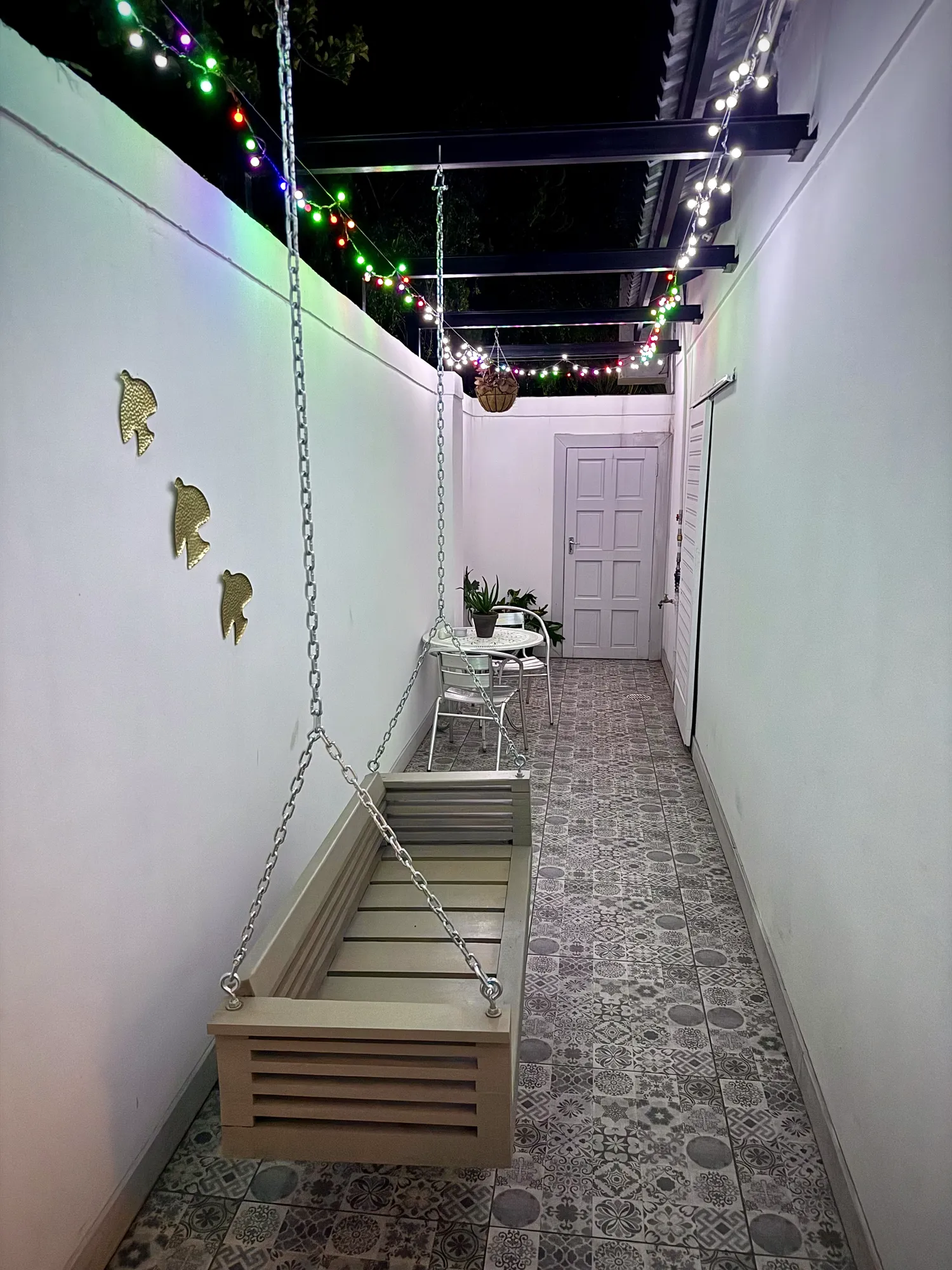 Birch Luxury Studio private patio with a wooden hanging bench and string lights