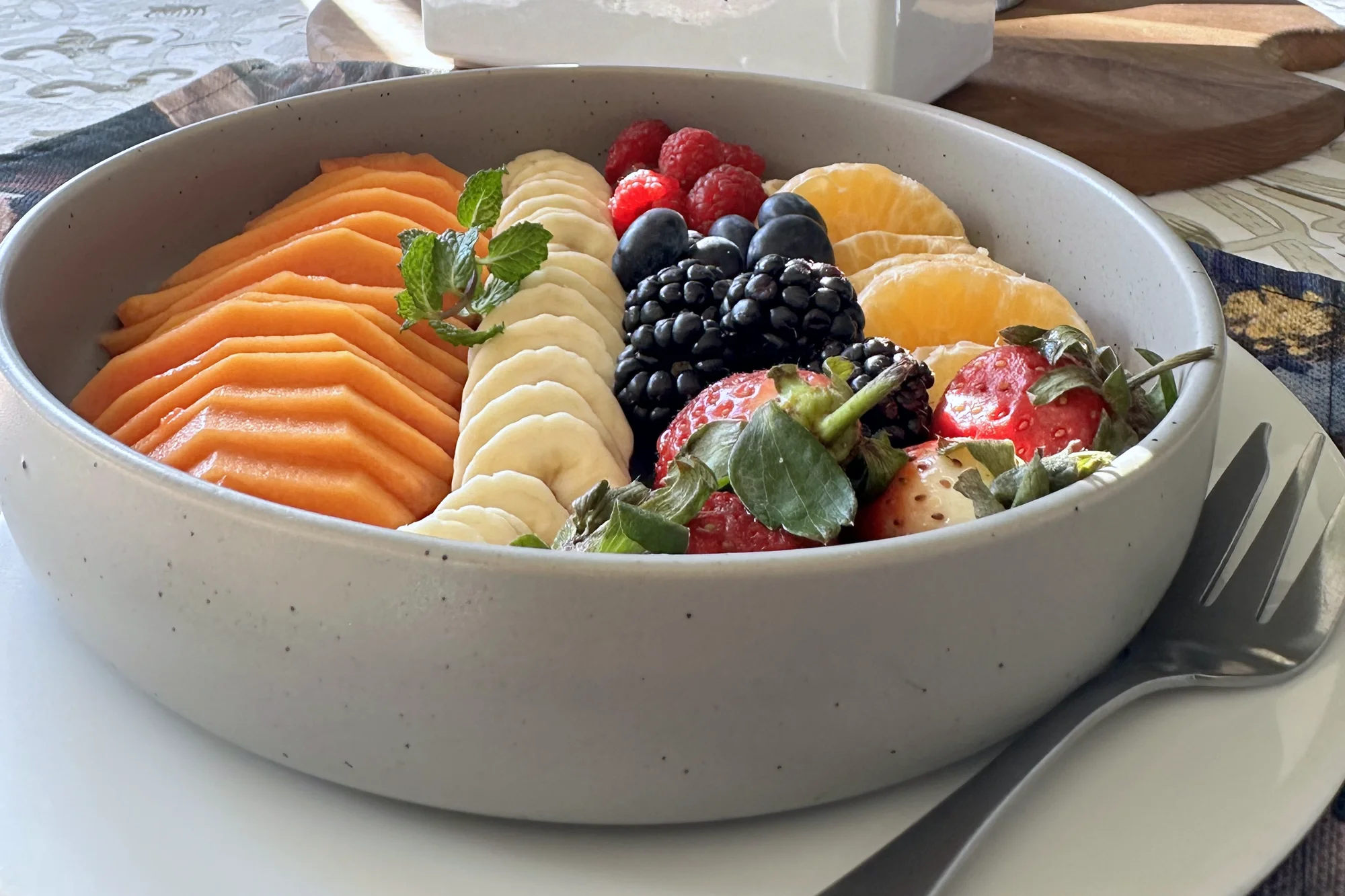 A breakfast bowl of fresh papaya, banana, berries and naartjie segments