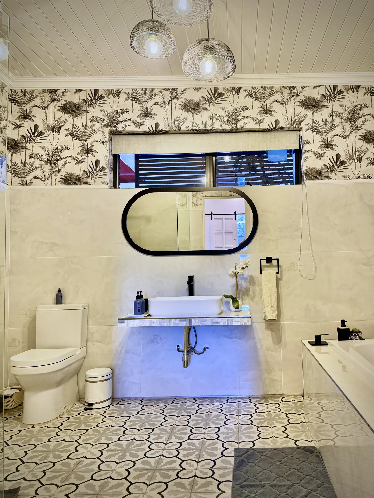 Cedar Luxury Studio bathroom with patterned tiles, pendant lights and an oval mirror