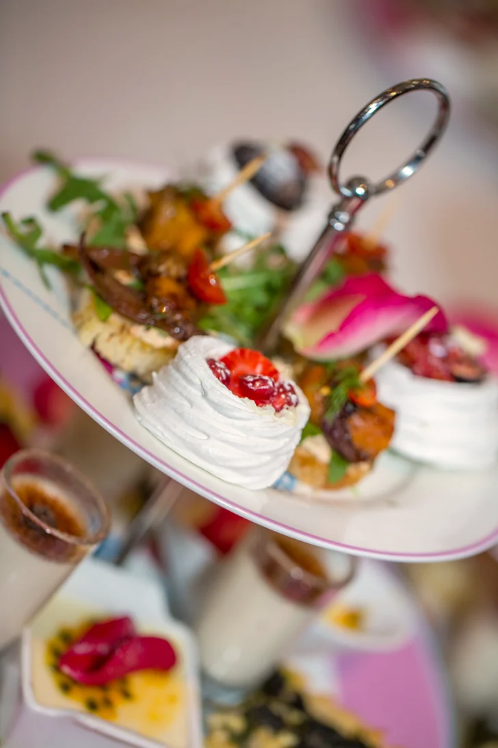 A tiered high tea stand with mini pavlovas, berries and savoury bites
