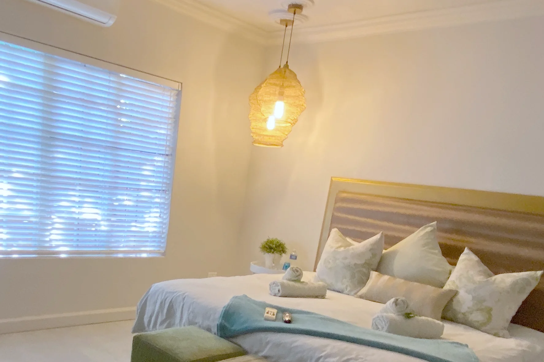Luxury North Suite: king bed with a gold headboard, woven pendant light and a large window