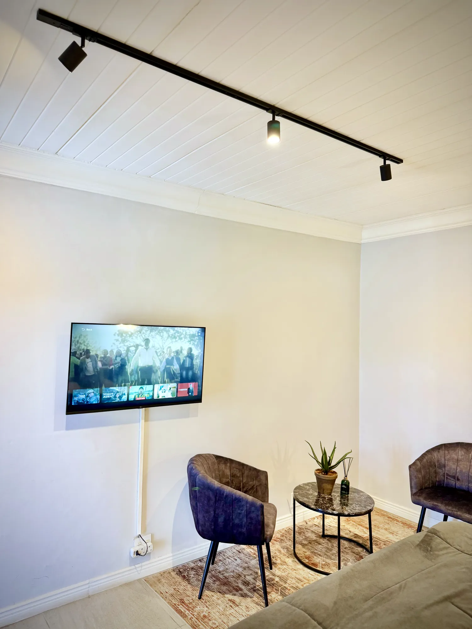 Oak Luxury Studio seating area with velvet chair, side table and wall-mounted Smart TV