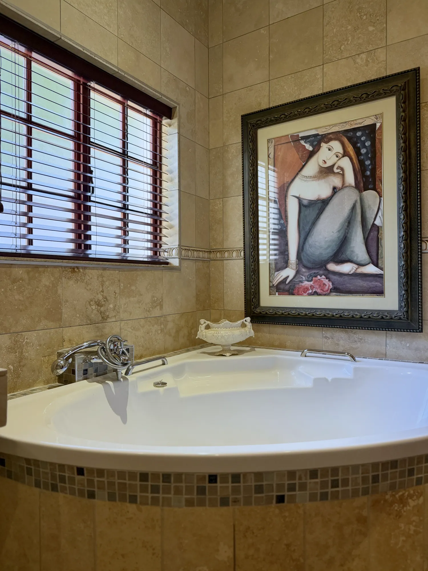 Luxury South Suite corner bath with mosaic trim and framed art