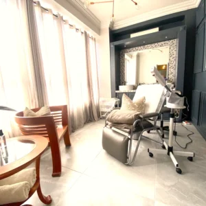Spa treatment room with a facial chair, steamer and sheer curtains