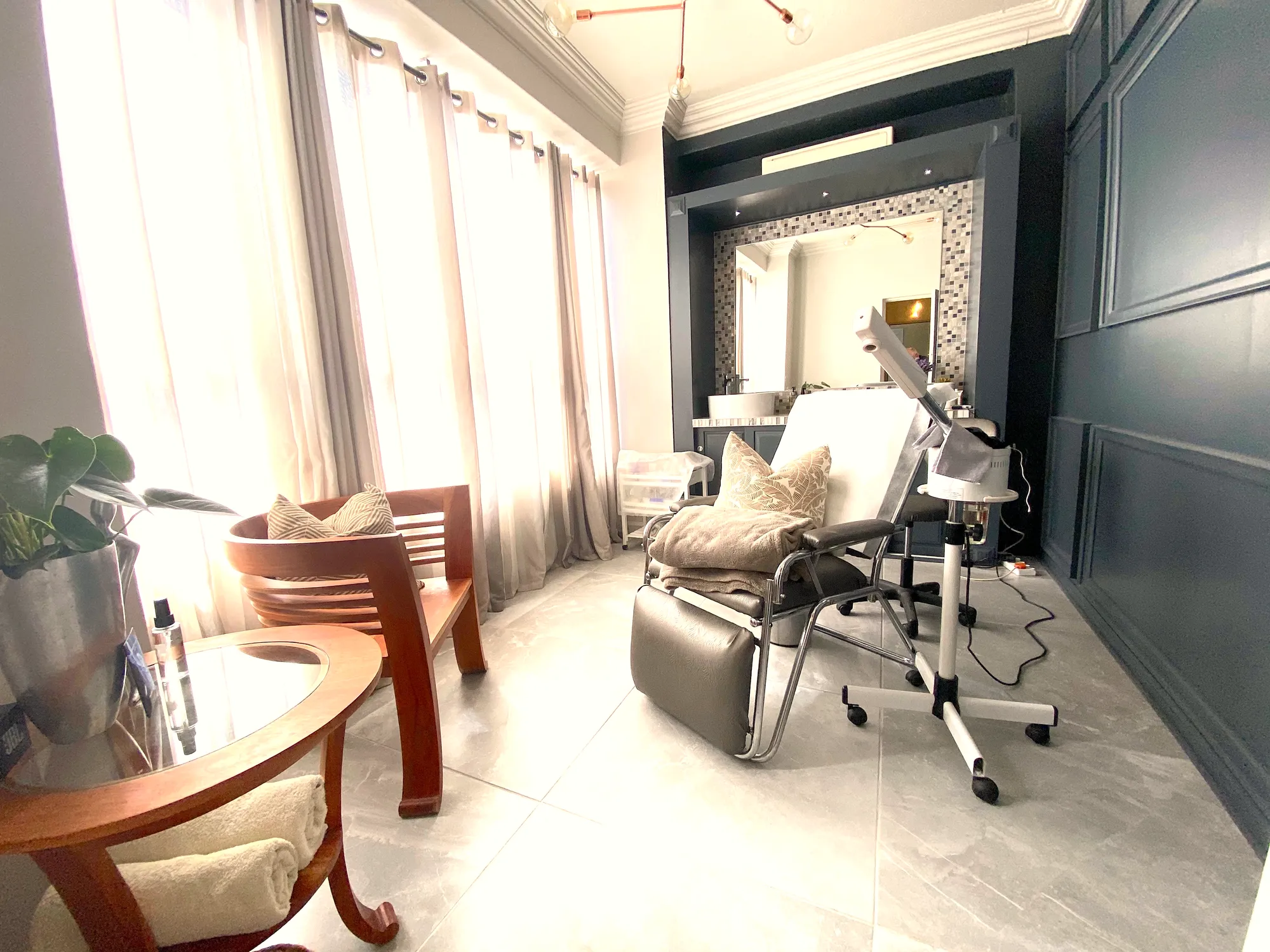 Spa treatment room with a facial chair, steamer and sheer curtains